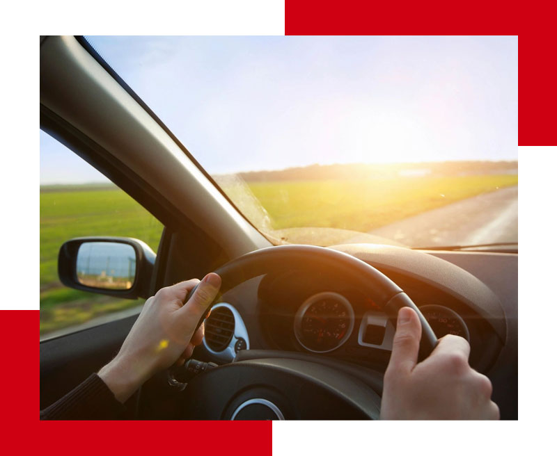 A person driving in the sun on a road.